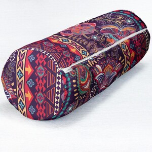 May include: A cylindrical bolster pillow featuring a dark purple base with a vibrant, multi-colored pattern of paisley, floral motifs, and geometric shapes in shades of red, yellow, orange, and teal, complete with a white zipper along the side.