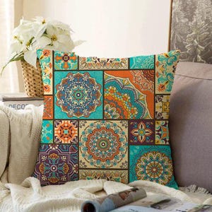 May include: A square throw pillow featuring a patchwork design of various geometric and mandala patterns in vibrant shades of turquoise, orange, purple, and yellow. The fabric displays a repeating grid of intricate, symmetrical motifs.