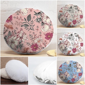 Può includere: Cuscini rotondi decorativi con motivi floreali. I cuscini presentano vari design, tra cui sfondi rosa, bianchi e blu con illustrazioni botaniche di fiori e foglie. I cuscini sono rotondi e hanno un bordo bianco.