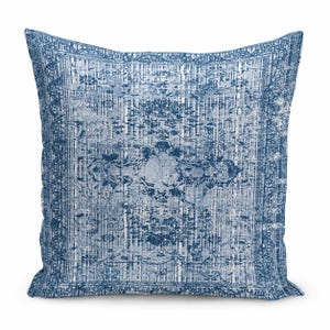May include: A square throw pillow featuring a distressed, faded blue and white pattern. The design includes a central medallion motif surrounded by intricate floral and geometric borders, mimicking the appearance of a worn area rug.