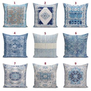 May include: A collection of nine square throw pillows featuring various blue, white, and beige patterns. Each pillow displays distinct geometric, floral, or medallion designs with a distressed, weathered texture across the fabric surfaces.