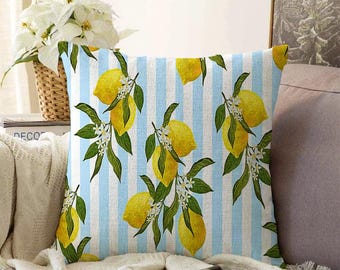 May include: A square throw pillow cover featuring a pattern of bright yellow lemons, green leaves, and small white blossoms set against a background of vertical light blue and white stripes. The fabric has a textured, woven appearance.