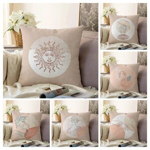 May include: A collection of decorative throw pillows with various designs. One pillow features a sun face within a circle. Other pillows display line art of classical busts and figures, set against soft pastel backgrounds. The pillows are square and made of a neutral-toned fabric.