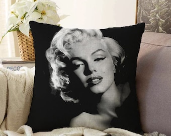 May include: Black and white throw pillow featuring a portrait of Marilyn Monroe. The pillow has a black background and a close-up image of Marilyn Monroe's face.