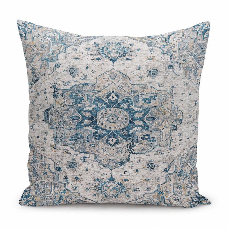 May include: A square throw pillow featuring a detailed, symmetrical medallion pattern in shades of deep blue, light blue, and beige. The design incorporates intricate floral and geometric motifs across the entire surface of the fabric.