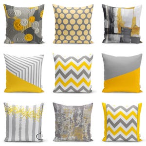 Può includere: Nove cuscini decorativi con una varietà di motivi geometrici in tonalità di grigio e giallo. I cuscini sono disposti in tre file di tre.
