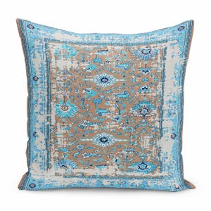 May include: A square throw pillow featuring a distressed, faded-look pattern in shades of light blue, white, and tan. The design includes intricate floral and geometric motifs with a prominent border, creating a weathered, vintage-inspired appearance.