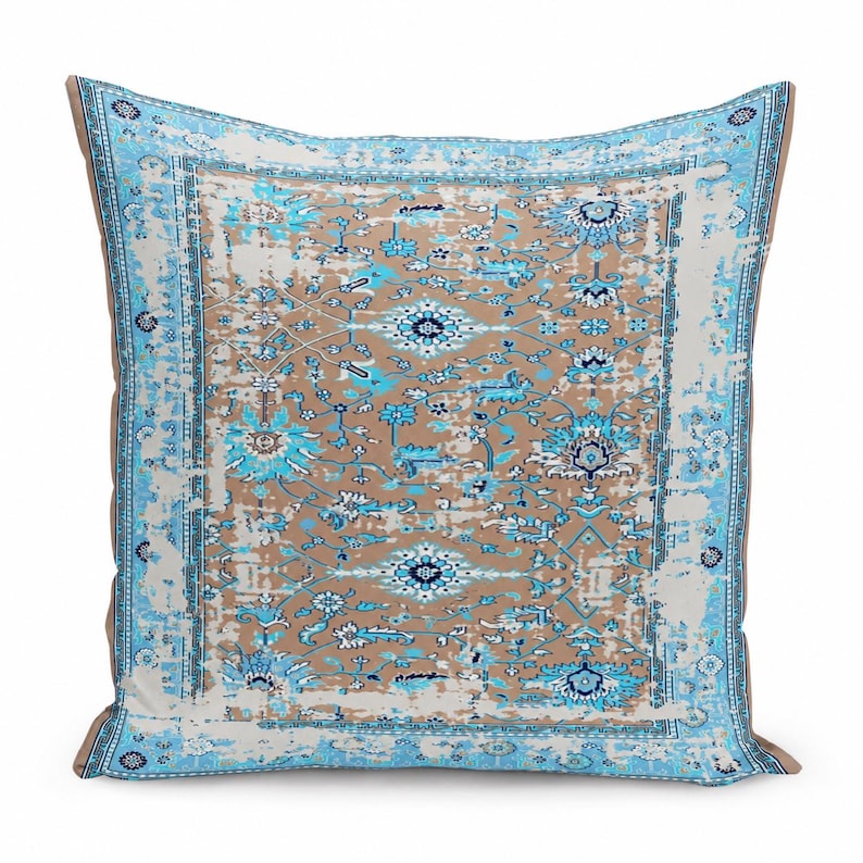 May include: A square throw pillow featuring a distressed, faded-look pattern in shades of light blue, white, and tan. The design includes intricate floral and geometric motifs with a prominent border, creating a weathered, vintage-inspired appearance.