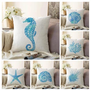 May include: Set of six decorative throw pillows with a coastal theme. Each pillow features a different blue watercolour design of a seahorse, seashell, coral, starfish, seashell, and a spiky sea creature.