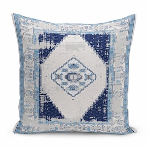 May include: A square throw pillow featuring a distressed, vintage-inspired pattern in shades of navy blue, light blue, and white. The design includes a central diamond motif surrounded by intricate geometric borders and floral accents.