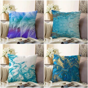 May include: Four decorative throw pillows with abstract designs. One pillow features a blue and purple feather design. Another has a blue and gold marbled pattern. The other two pillows have blue and white abstract patterns.