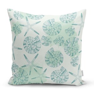 Peut inclure: Un coussin blanc avec un motif de coquillages et d'&eacute;toiles de mer bleu sarcelle. Le coussin a un fond aquarelle vert clair.