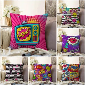 Peut inclure: Ensemble de coussins décoratifs avec des motifs pop art. L'un des coussins présente un téléviseur rétro avec le mot "WOW!" dans une bulle. D'autres coussins affichent des graphiques de style bande dessinée, dont des lèvres, des cœurs et les mots "Kiss" et "Try Me!"