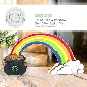 以下が含まれることがあります： 虹の形をした木製の棚の飾りで、端には金の壺があります。虹は赤、オレンジ、黄色、緑、青、藍色、紫に塗られています。金の壺は黒で、クローバーと金貨が付いています。