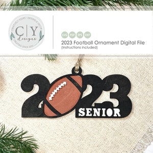 May include: A black wooden ornament shaped like the numbers 2023 with a brown football cut out of the centre. The word "SENIOR" is written below the numbers.