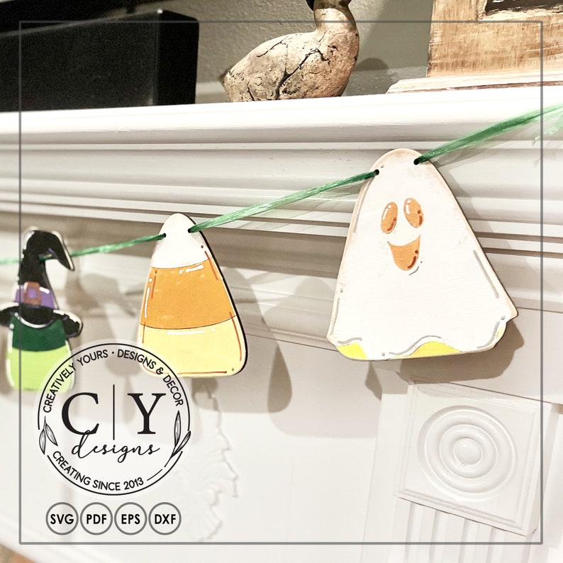 Puede incluir: Un banner de Halloween con una cinta verde y recortes de madera de una bruja, ma&iacute;z dulce, un fantasma y el texto "Creatively Yours - Designs & Decor CY Designs Creating Since 2013".