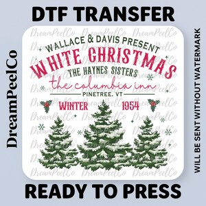 May include: A DTF transfer featuring the text "WHITE CHRISTMAS" in red script, with the names "WALLACE & DAVIS PRESENT" and "THE HAYNES SISTERS" above. Below are three snow-covered evergreen trees and the words "READY TO PRESS".