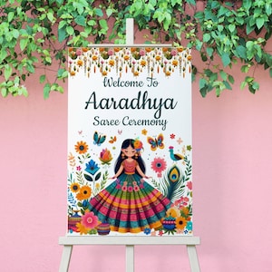 May include: Welcome to Aaradhya Saree Ceremony sign with a colorful illustration of a girl in a traditional Indian saree, surrounded by flowers and butterflies.