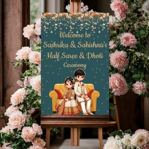 May include: A teal blue welcome sign with gold lettering and a floral border. The sign reads "Welcome to Sashrika & Sahishni's Half Saree & Dhoti Ceremony". The sign also features a cartoon illustration of a couple sitting on a yellow sofa.
