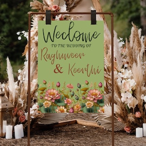 May include: A green welcome sign with floral accents and the text "Welcome to the wedding of Raghuveer & Keerthi".