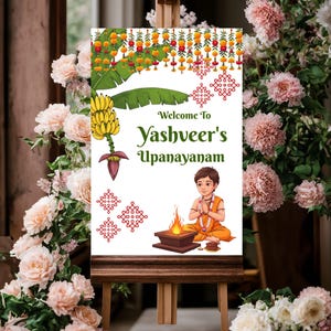 Może przedstawiać: Ozdobny znak na drewnianym sztaludze z napisem "Welcome to Yashveer's Upanayanam". Znak zawiera ilustracje kwiatów, kiść bananów i postać z kreskówki w pomarańczowych ubraniach. Tło zdobią różowe kwiaty.