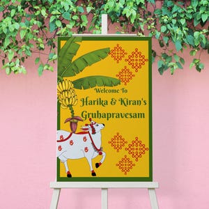 May include: A welcome sign for Harika & Kiran's Gruhapravesam, featuring a yellow background with green accents. The sign includes a drawing of a white cow with red details, banana leaves, and text. The sign is displayed on a white easel.