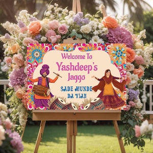 May include: A colourful welcome sign with a floral design and the text "Welcome to Yashdeep's Jaggo, Sade Munde Da Yaar". The sign features illustrations of a man and woman in traditional Indian clothing.