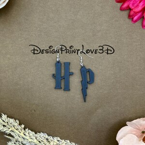 May include: Dark blue earrings featuring the letters "HP" and a lightning bolt design. The earrings are suspended from silver-colored fish hook ear wires. The image also includes the text "Design Print Love 3D".