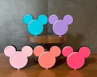 May include: Five Mickey Mouse shaped balloons in different colors. The balloons are pink, light pink, coral, purple, and blue.