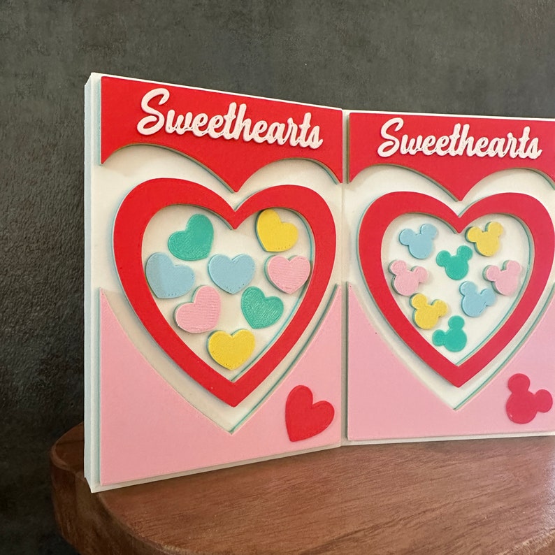 May include: Two white cardstock Valentine's Day cards with red hearts and the text "Sweethearts" on each card. The hearts are filled with colorful candy hearts and Mickey Mouse heads.