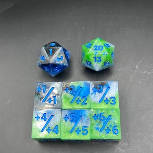 Può includere: Un set di dadi in resina fatti a mano per giochi da tavolo. Include un D20 blu e argento, un D20 verde e argento e sei dadi quadrati con numeri e simboli blu su sfondi verdi e blu.