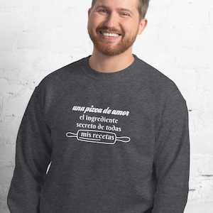 May include: A dark gray sweatshirt with a white graphic that reads "una pizca de amor el ingrediente secreto de todas mis recetas" with a rolling pin graphic.