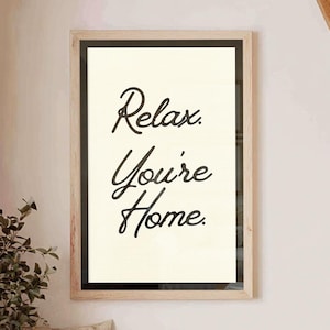 May include: A framed print with the words "Relax. You're Home." hangs above a wooden bench with pillows. The room has a rustic aesthetic, with wooden beams and a woven rug. Decorative plants in vases and baskets add to the cozy atmosphere.