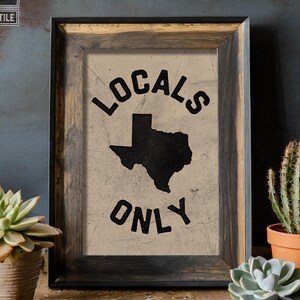 May include: A framed print with a distressed, beige background featuring a black silhouette of the state of Texas with the text "Locals Only" in a black, distressed font.