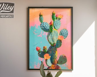 May include: A framed print of a colorful cactus with pink, orange, and green hues. The cactus is in a black frame and is hanging on a white wall. There are three potted plants on a wooden table in front of the print.