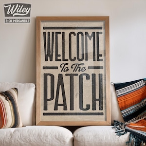 May include: A framed print with a vintage-style design that says "Welcome to the Patch" in black text on a beige background.