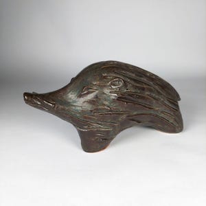 May include: A ceramic sculpture of a stylized hedgehog with a brown and green glaze. The sculpture is in a running pose with its head tilted down.