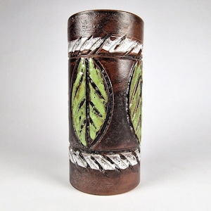 May include: A cylindrical brown ceramic vase with a textured surface. The vase features green leaf designs and white, textured bands. The vase is approximately 8 inches tall.