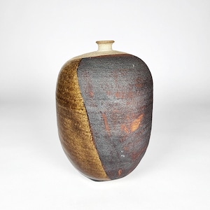 May include: A handcrafted ceramic vase with a unique, asymmetrical design. The vase features a combination of brown, black, and tan hues, with a textured surface. The vase has a rounded body and a small, cylindrical neck, perfect for displaying flowers or as a decorative piece.