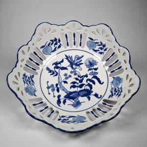 May include: White and blue porcelain serving dish with a scalloped edge and openwork design. The center features a blue floral and bird motif. The rim is trimmed with a dark blue border. A decorative piece for serving or display.