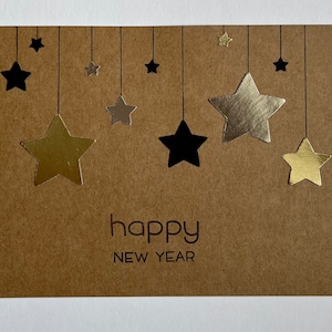 May include: A brown card with a happy new year message and gold and black stars hanging from strings.