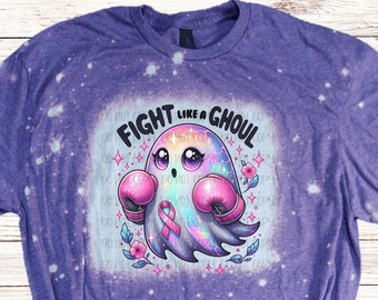 May include: Purple t-shirt with a bleached design featuring a cartoon ghost wearing pink boxing gloves and a pink ribbon. The text "FIGHT LIKE A GHOUL" is above the ghost.