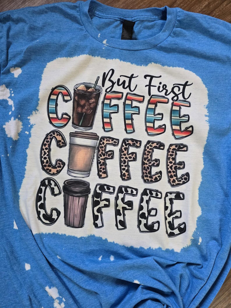 May include: A blue tie-dye t-shirt with a white graphic that says "But First Coffee" with three coffee cups in different styles.