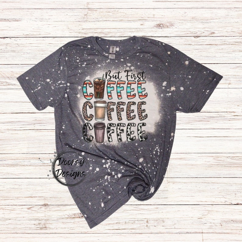 May include: A gray t-shirt with a bleach-splattered design featuring the text "But First Coffee" with three coffee cups in different styles.