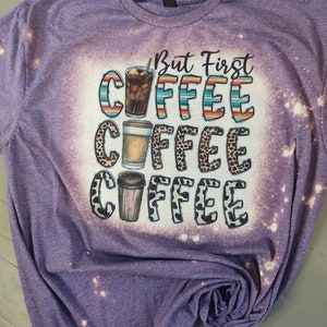 May include: Purple t-shirt with a bleached design featuring the text "But First Coffee" with three coffee cups in different styles.