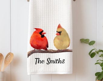 Op de afbeelding: Witte keukendoek met een rode kardinaal en een gele kardinaal die op een tak zitten. De handdoek heeft de tekst "The Smiths" erop gedrukt.