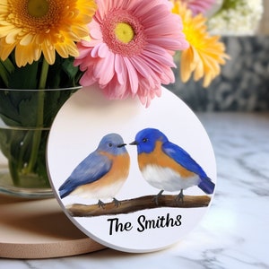 Könnte beinhalten: Ein runder weißer Untersetzer mit einem Paar Blaumeisen, die auf einem Ast sitzen. Der Untersetzer ist mit dem Text "The Smiths" personalisiert.