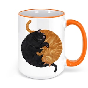 May include: White ceramic mug with an orange rim and handle. The mug features a black and orange cat illustration in a yin yang design.