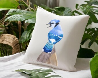 May include: A white throw pillow with a blue jay illustration. The bird is perched on a branch and has a blue and white body with a black head and beak.