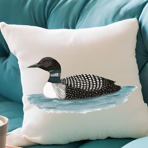 Op de afbeelding: Een wit kussen met een zwart-witte illustratie van een duiker die in blauw water zwemt.